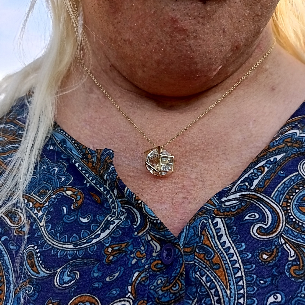 Gold necklace with a clear stone in the middle.